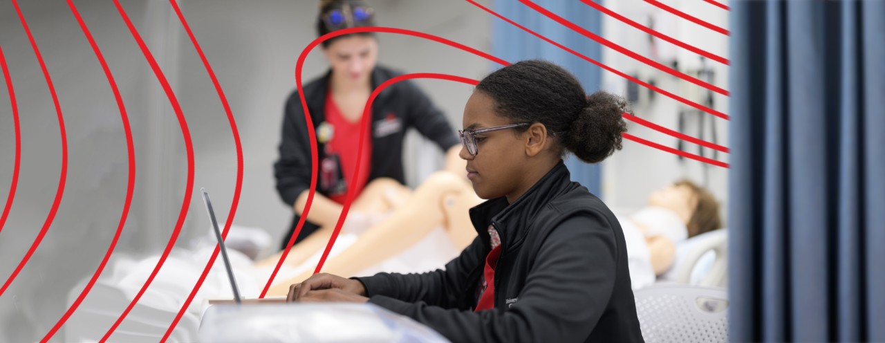 student by laptop in sim lab